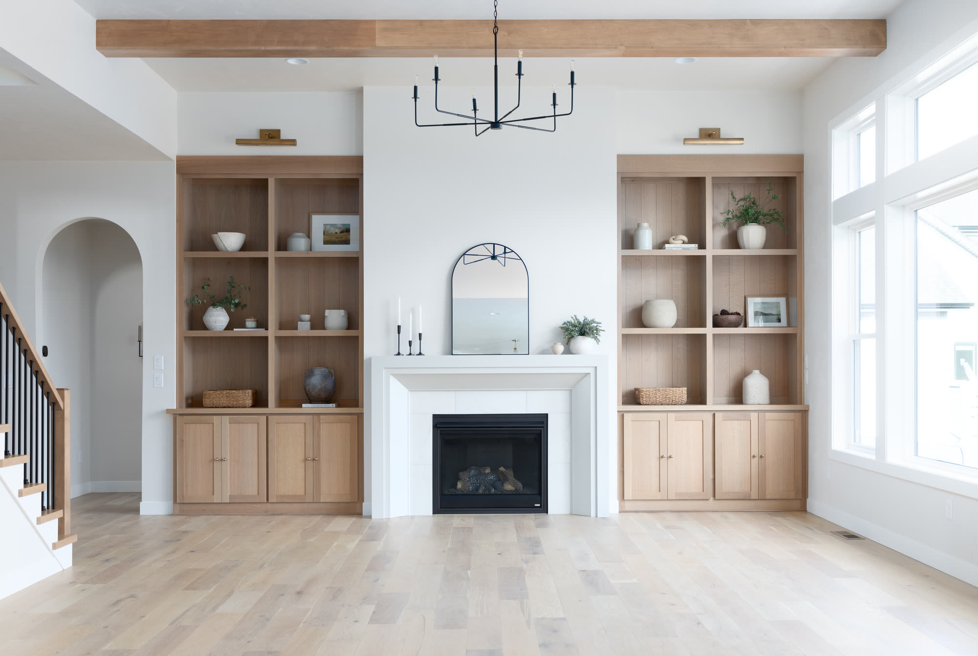 Living room with oak built-in shelves around a fireplace, under a wood beam, in a Silvertree home