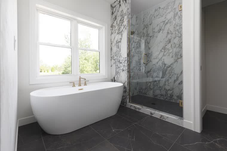 Primary bath with a freestanding tub, a marble shower and dark floor tile