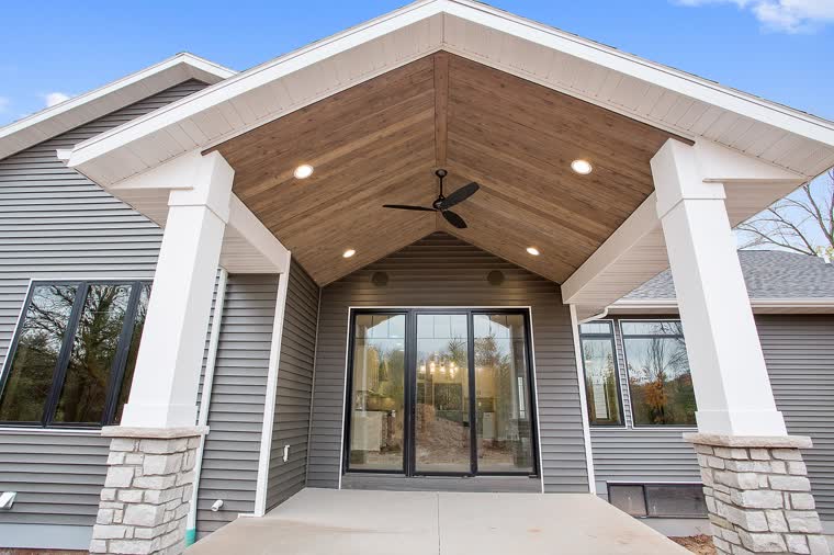 Covered back patio with a wood ceiling, white columns and stone bases