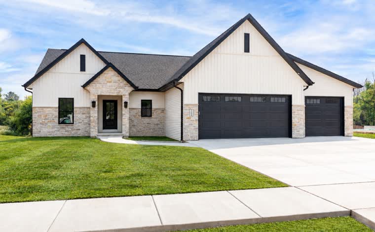 White ranch home with black garage doors and a stone front