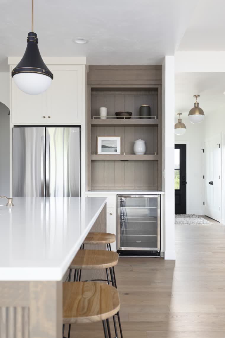 Kitchen island with wood stools, looking toward an oak pantry wall and beverage fridge
