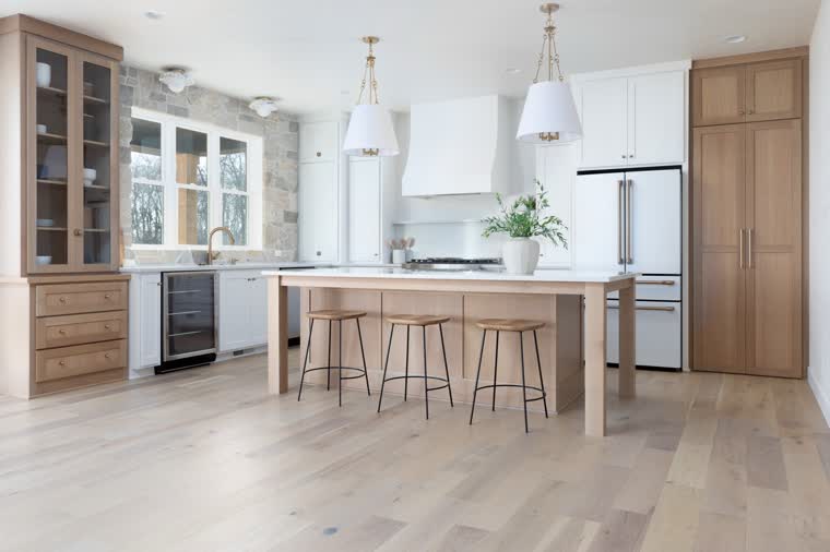 Kitchen with oak cabinets, a long island with stools and white pendant lights