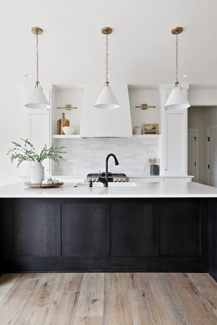 Black kitchen island under three white pendant lights