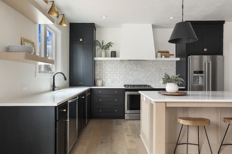 Kitchen with black cabinets, an oak island and a white range hood
