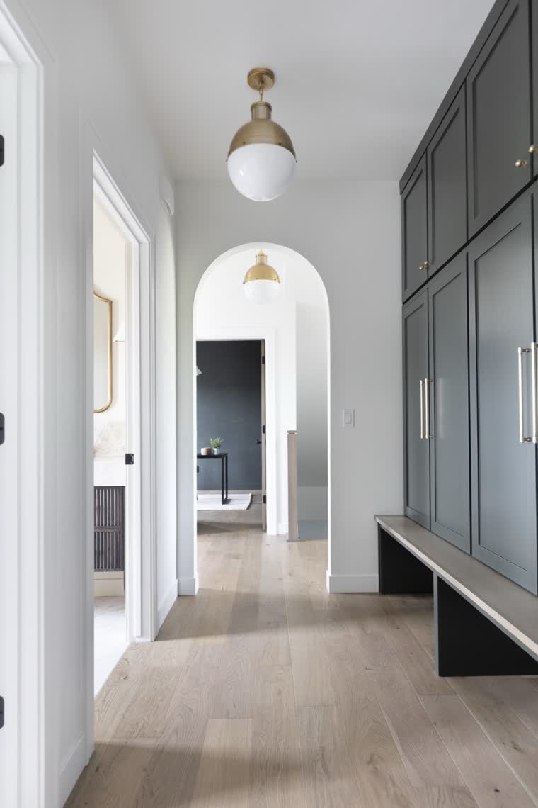 Hallway with a dark built-in locker wall and bench, leading to an arched doorway