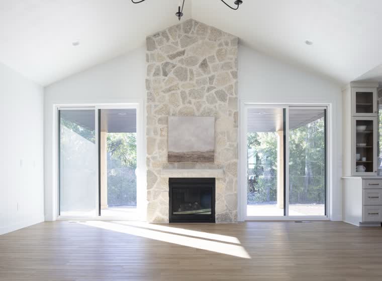 Vaulted great room with a floor-to-ceiling stone fireplace between two patio doors