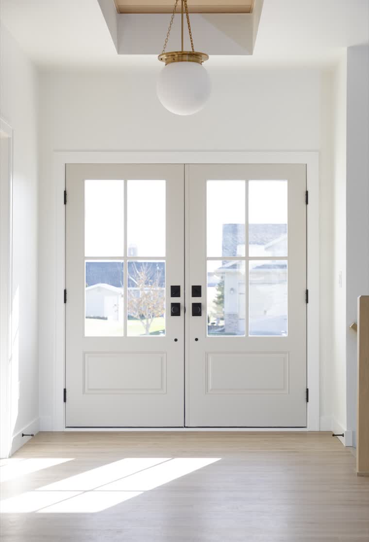 Entry with white double doors and a globe pendant light