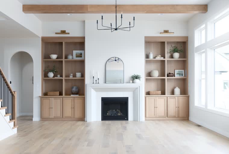 Living room with oak built-in shelves around a fireplace, under a wood beam