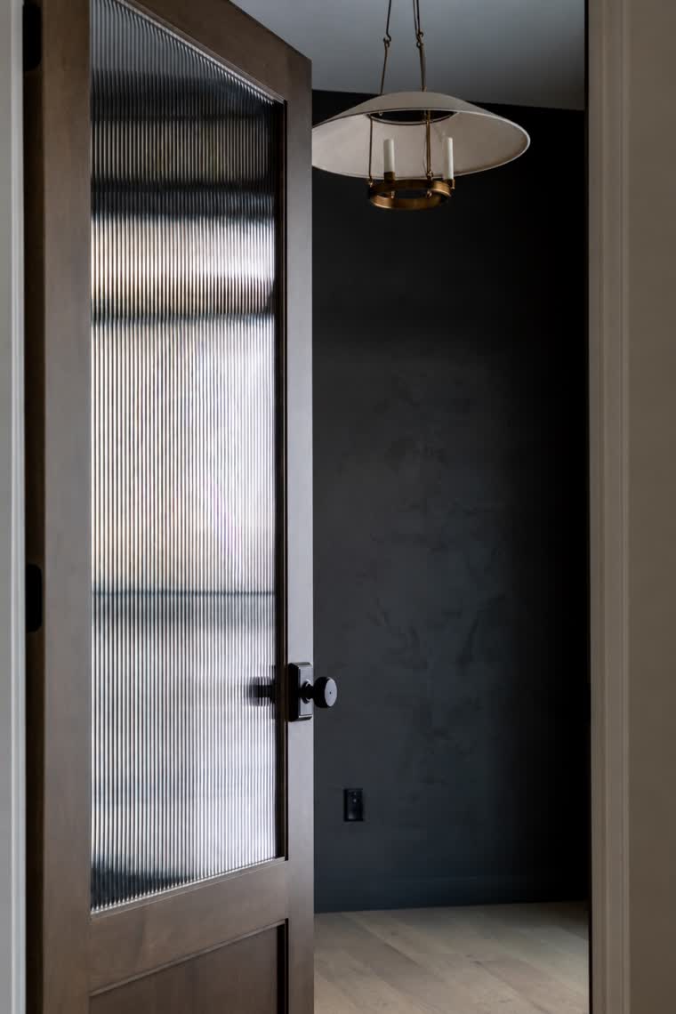 Doorway with a ribbed-glass wood door opening to a dark-walled room